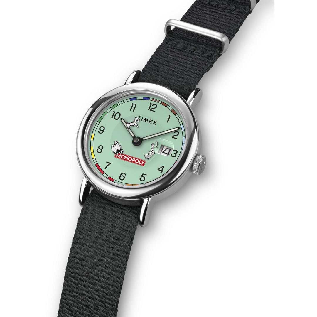 Zegarek Timex z tarczą inspirowaną grą Monopoly w okrągłej kopercie na materiałowym pasku
