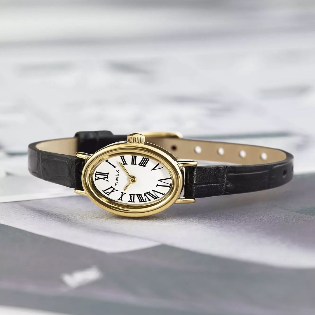 Zegarek Timex o delikatnym, kobiecym wyglądzie ze smukłą, owalną kopertą i białą, prostą tarczą z cyframi rzymskimi