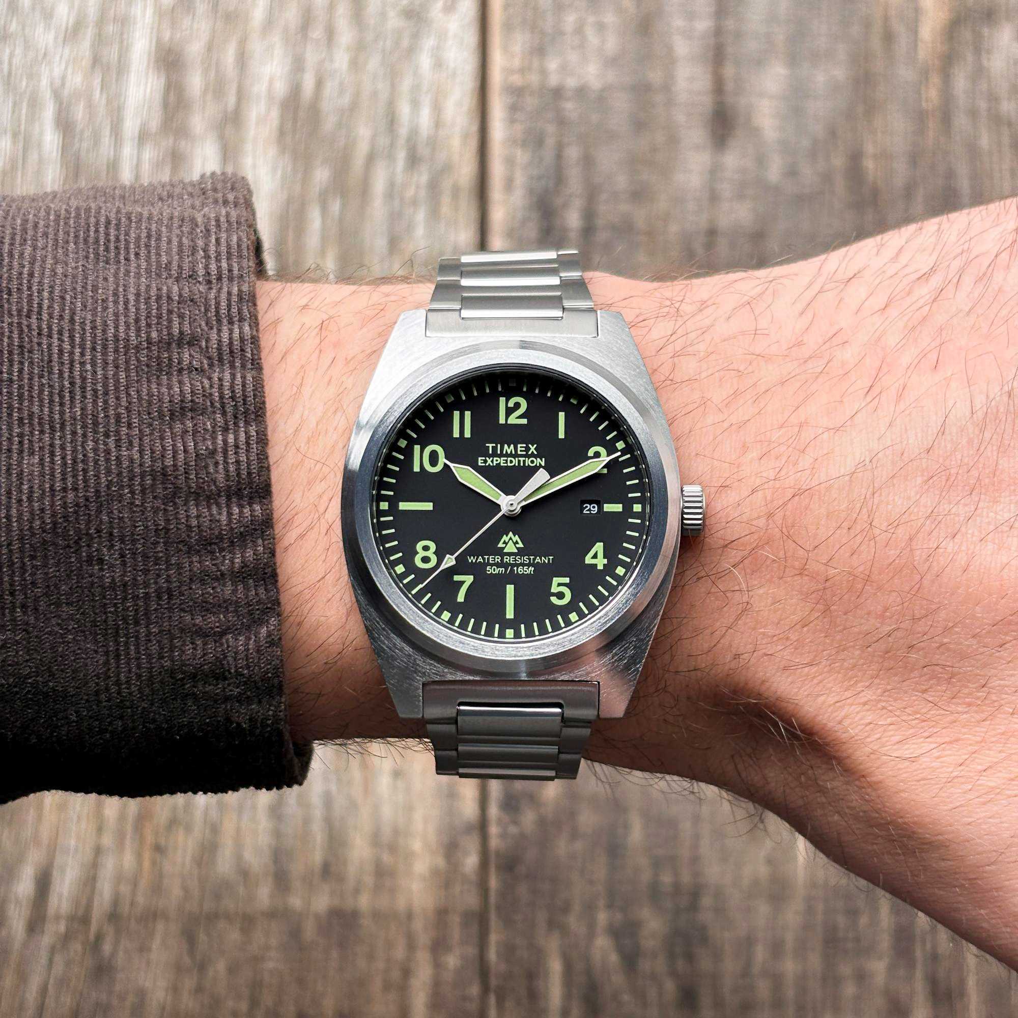Timex Expedition Field TW2Y18300 z czarną tarczą i zielonymi cyframi na stalowej bransolecie na nadgarstku, rękaw sztruksu