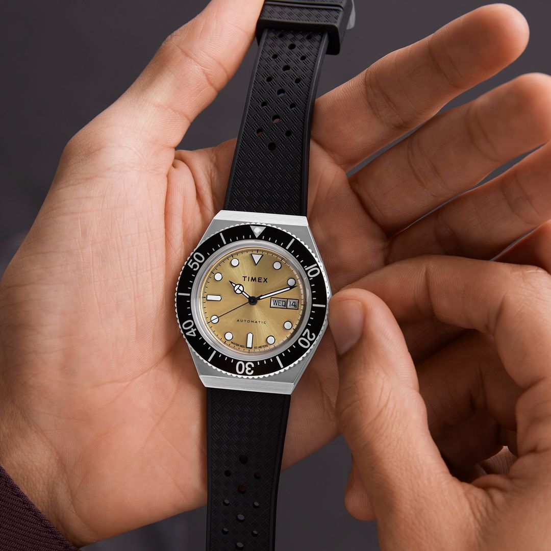 Zegarek męski Timex ze złotą tarczą, czarnym bezelem, srebrną kopertą i czarnym paskiem