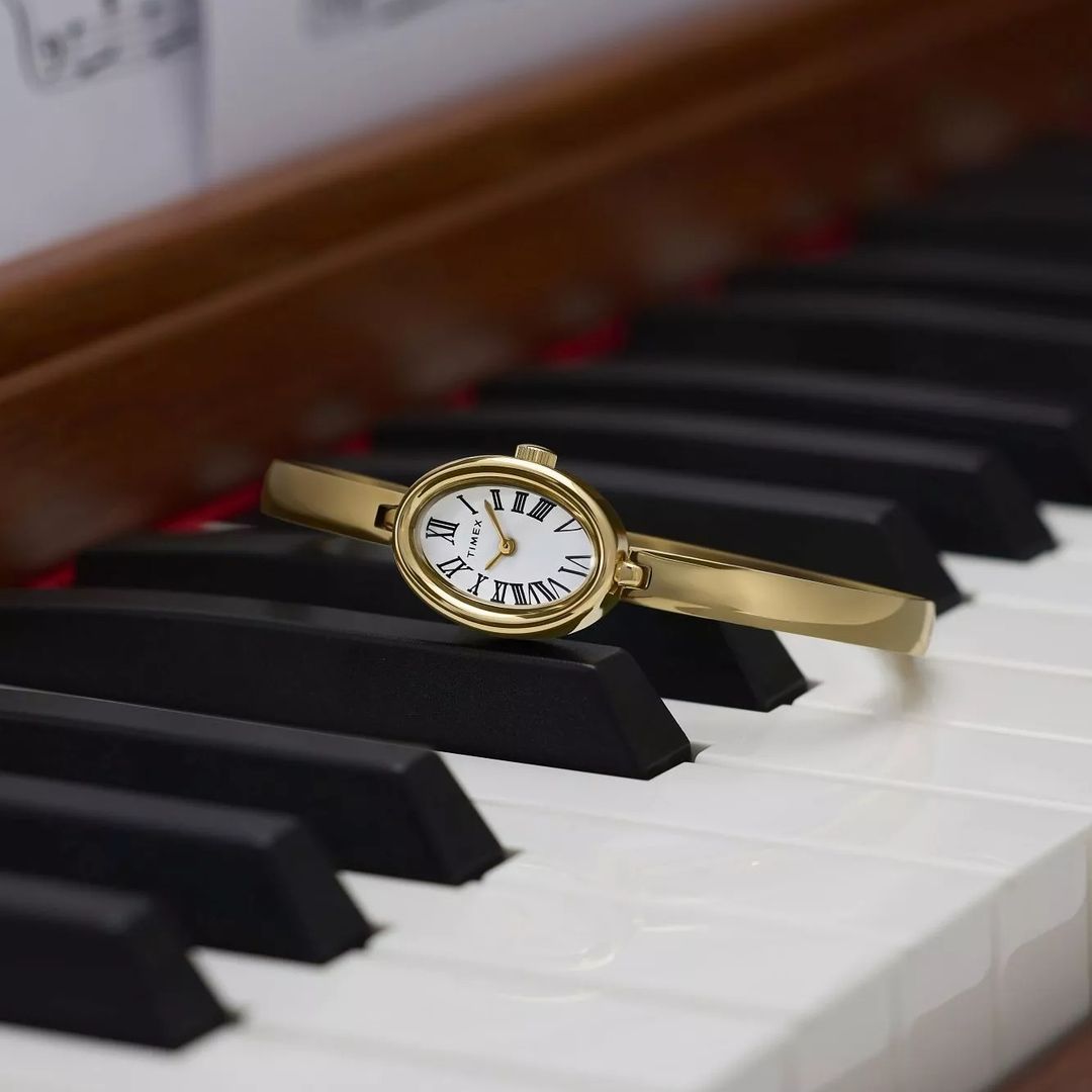 Zegarek damski Timex w złotej kolorystyce z owalną kopertą, z białą tarczą i czarnymi cyframi rzymskimi ze złotymi wskazówkami