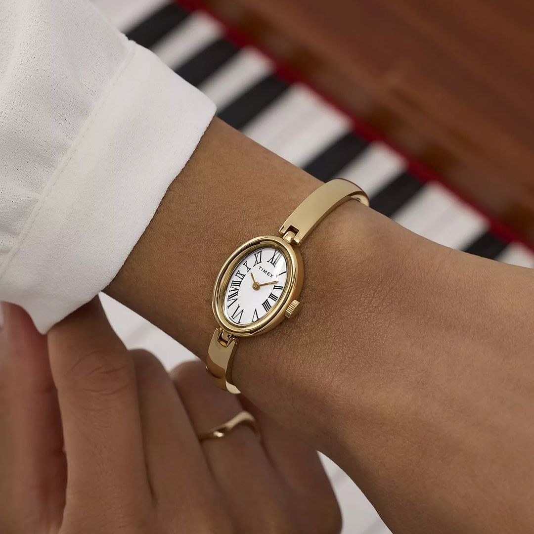 Zegarek damski Timex w złotym kolorze z białą tarczą oraz czarnymi indeksami rzymskimi w smukłej kopercie